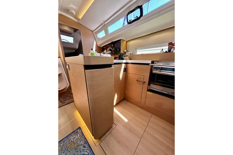 Slide: The Image of Modern kitchen interior of 2022 Jeanneau Sun Odyssey 410 yacht, featuring wood cabinetry and appliances. - 56