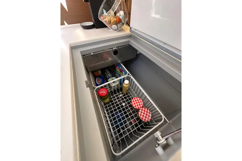 Slide: The Image of Interior view of Jeanneau Sun Odyssey 410's refrigerator, showcasing organized food storage. - 60