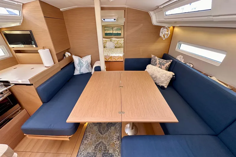 Slide: The Image of Interior of 2022 Jeanneau Sun Odyssey 410 sailboat with blue seating and wooden table. - 69