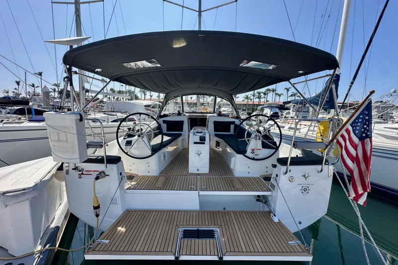 Slide: The Image of 2022 Jeanneau Sun Odyssey 410 sailboat with dual steering wheels and American flag in marina. - 8