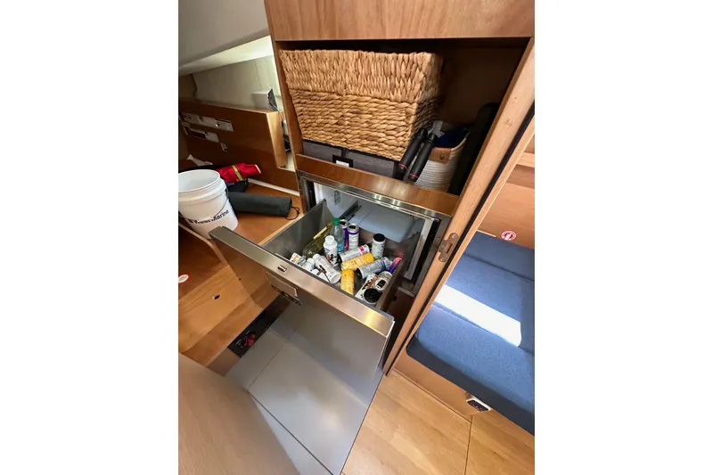 Slide: The Image of Interior of 2022 Jeanneau Sun Odyssey 410 with open storage drawer and wicker basket. - 98