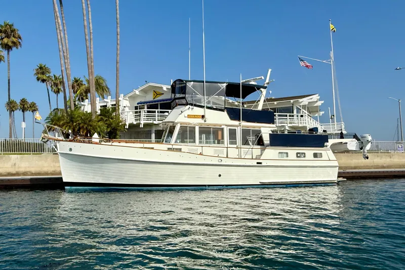 The Image of 1982 Grand Banks 42 Motoryacht docked near palm trees and waterfront building. - 0