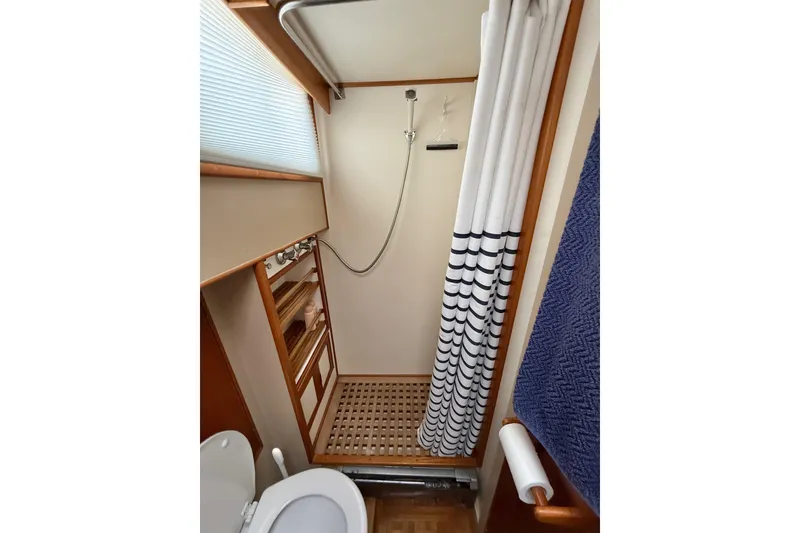 Slide: The Image of 1982 Grand Banks 42 Motoryacht bathroom with shower, wooden accents, and striped curtain. - 20