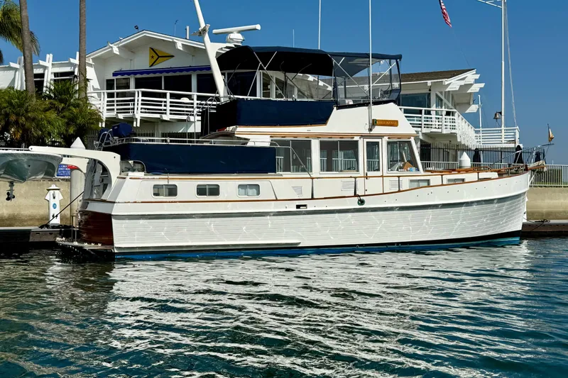 Slide: The Image of 1982 Grand Banks 42 Motoryacht docked at marina, with white exterior and blue canopy. - 4