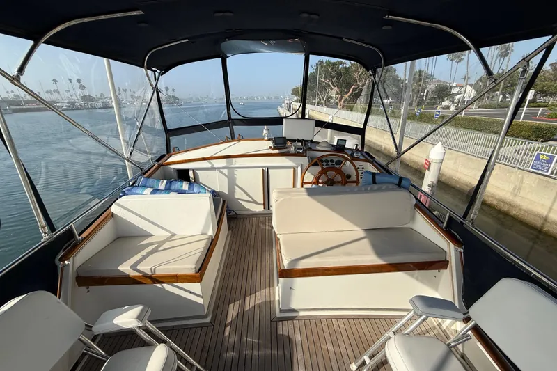 Slide: The Image of 1982 Grand Banks 42 Motoryacht interior with seating and steering wheel, docked by a canal. - 40