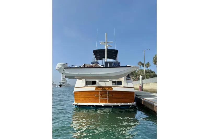 Slide: The Image of 1982 Grand Banks 42 Motoryacht docked, featuring classic wooden design and serene water backdrop. - 5