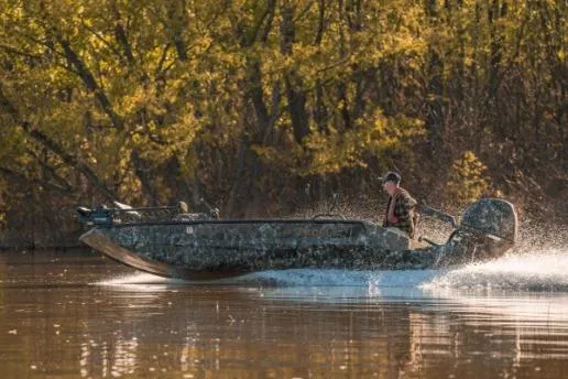 The Image of Man driving Excel 2172 Stalker CC boat on a calm river, surrounded by autumn trees. - 1