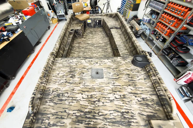 Slide: The Image of Camouflage-patterned Excel 1751 Viper F4 boat in a workshop, surrounded by tools and equipment. - 26