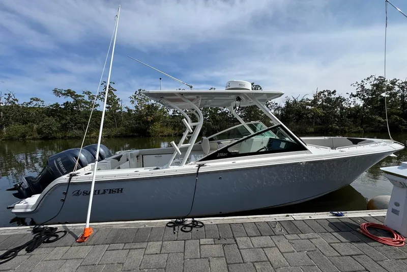 Slide: The Image of 2022 Sailfish 276 DC boat docked by a scenic riverside. - 2