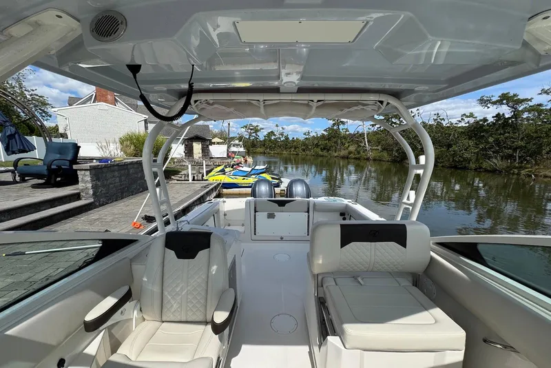 Slide: The Image of 2022 Sailfish 276 DC boat interior with seating, docked by a serene waterfront. - 24