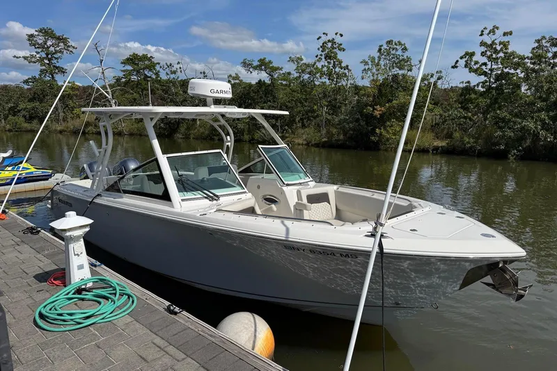 Slide: The Image of 2022 Sailfish 276 DC boat docked by a serene riverbank. - 3