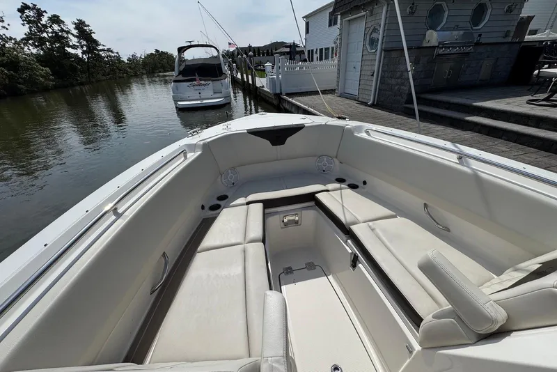 Slide: The Image of 2022 Sailfish 276 DC boat interior with spacious seating, docked near a waterfront home. - 31