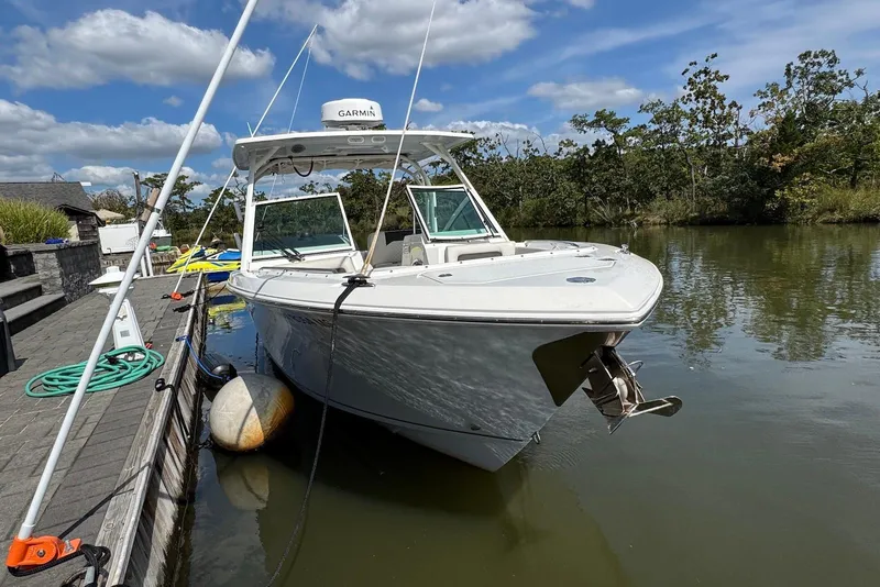 Slide: The Image of 2022 Sailfish 276 DC boat docked on a calm river under a blue sky. - 6