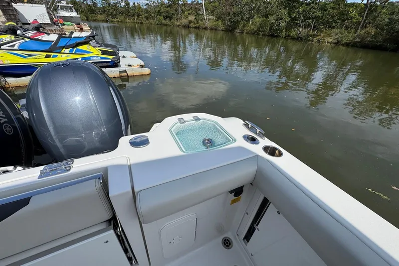 Slide: The Image of 2022 Sailfish 276 DC boat with motor, docked near watercrafts on a calm river. - 8