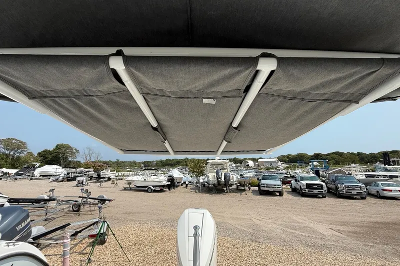 Slide: The Image of 2025 Cobalt R4 Outboard boat with canopy, parked in a marina with vehicles and trailers. - 16