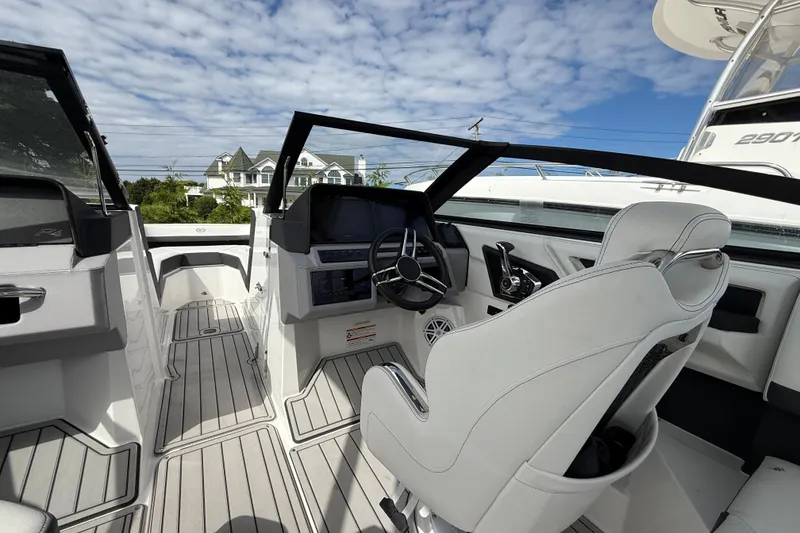 Slide: The Image of 2025 Cobalt R4 Outboard boat interior with modern helm and seating, under a blue sky. - 32