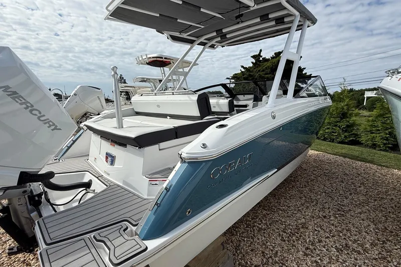 Slide: The Image of 2025 Cobalt R4 Outboard boat with Mercury engine, docked on gravel, under cloudy sky. - 4