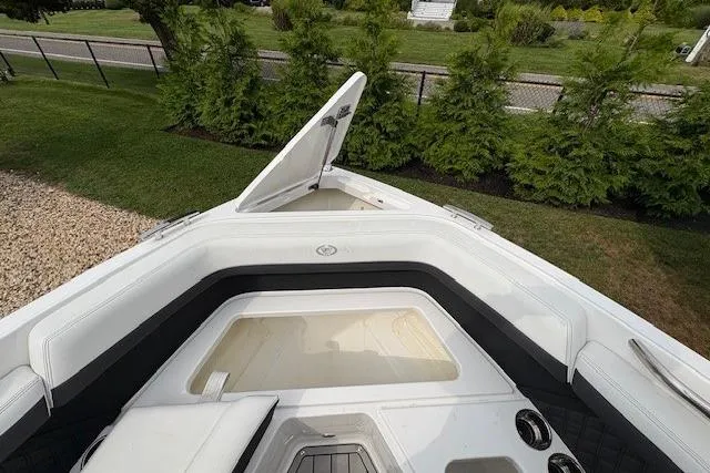 Slide: The Image of 2025 Cobalt R4 Outboard boat interior with open storage compartment, surrounded by greenery. - 46