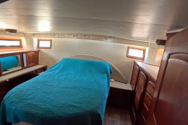Slide: The Image of 1987 Californian 45 Motor Yacht bedroom with blue bedding and wooden cabinetry. - 47