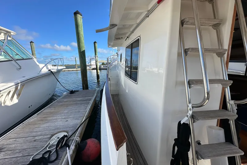 Slide: The Image of 1999 Kadey-Krogen 39 yacht docked, featuring American flag and spacious deck. - 49