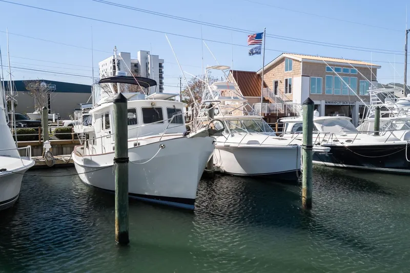 Slide: The Image of 1999 Kadey-Krogen 39 yacht docked at marina with other boats and buildings in background. - 56