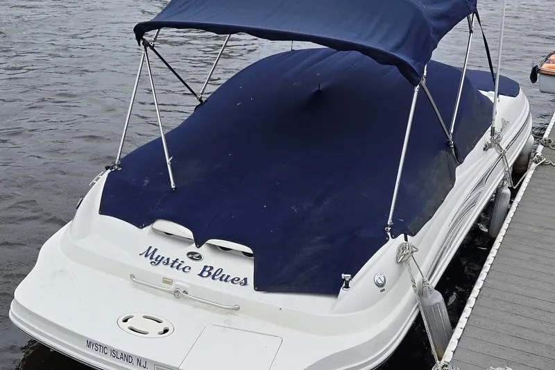 Slide: The Image of 2005 Sea Ray 220 Sundeck boat docked, covered with blue canopy, named "Mystic Blues". - 1