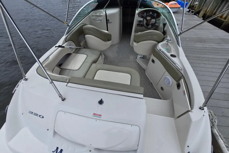 Slide: The Image of 2005 Sea Ray 220 Sundeck interior with seating and steering wheel, docked by the water. - 13
