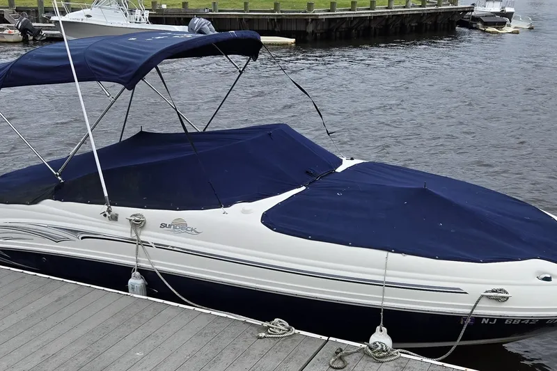 Slide: The Image of 2005 Sea Ray 220 Sundeck boat docked with blue cover and canopy. - 2