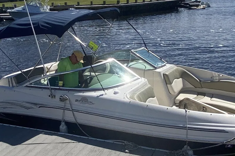 Slide: The Image of 2005 Sea Ray 220 Sundeck boat docked, featuring a blue canopy and spacious seating. - 22