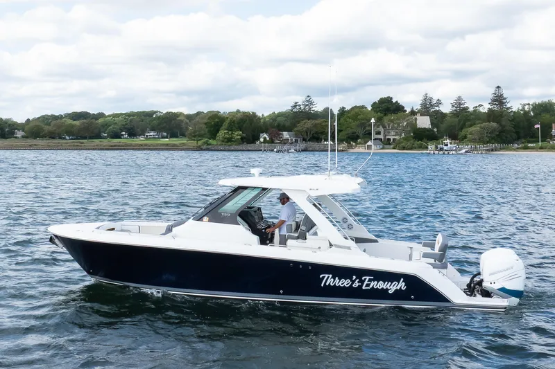Slide: The Image of 2020 Tiara Sport 34 LS boat cruising on a scenic lake with lush shoreline. - 6