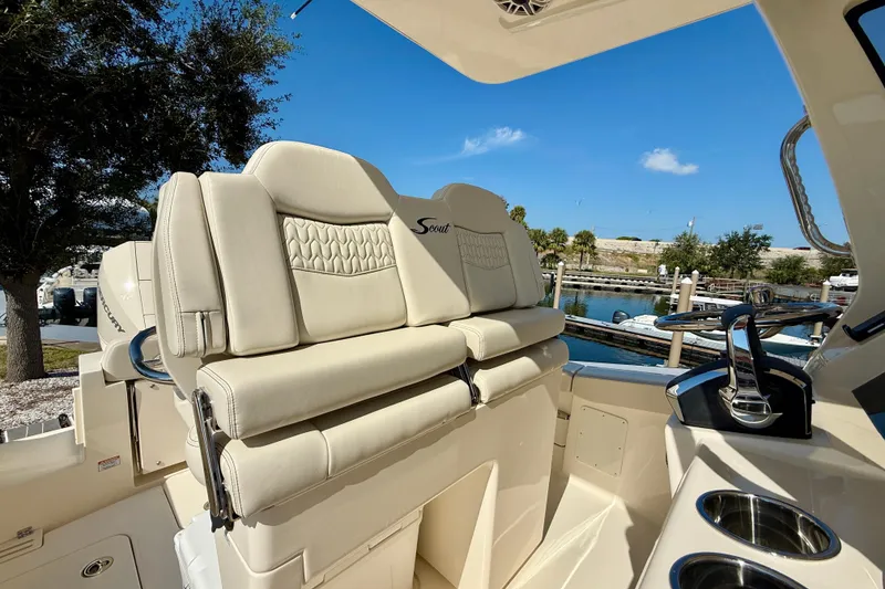 Slide: The Image of 2026 Scout 260 LXF boat interior with luxurious seating and steering wheel, dockside view. - 15