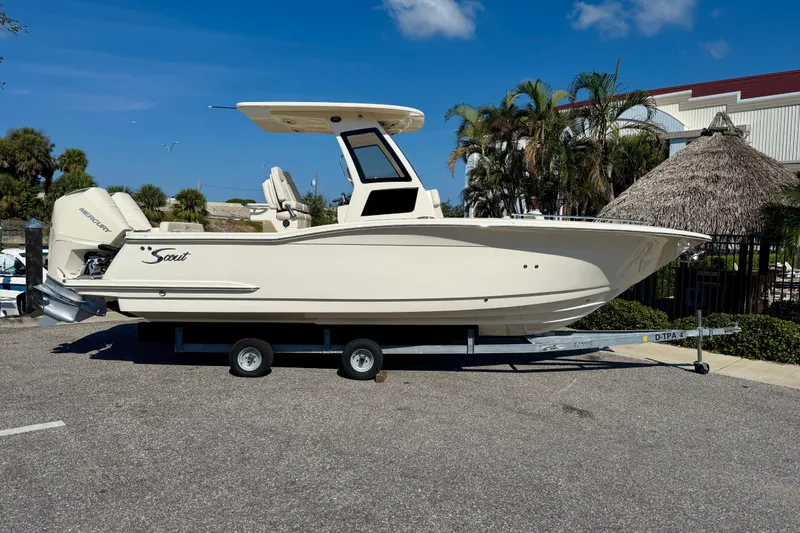 Slide: The Image of 2026 Scout 260 LXF boat on trailer, parked outdoors under clear blue sky. - 2
