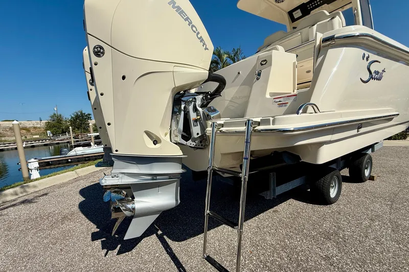 Slide: The Image of 2026 Scout 260 LXF boat with Mercury engine, ladder, and trailer in marina setting. - 6