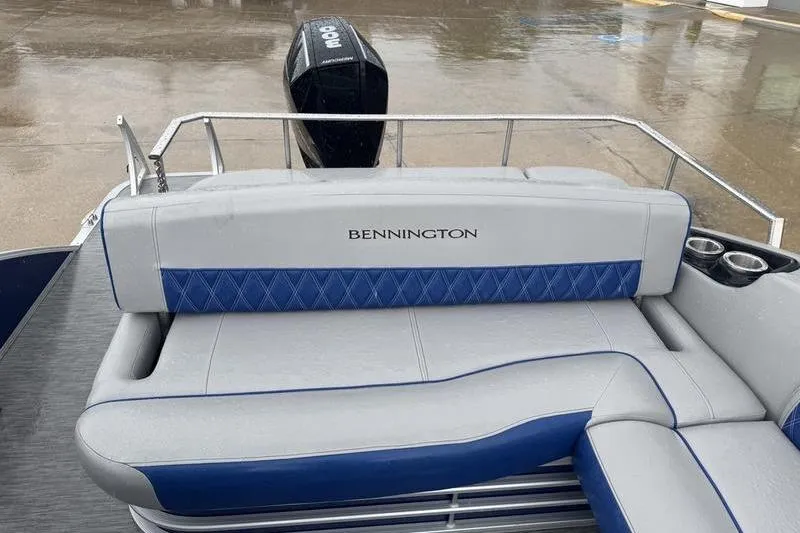 Slide: The Image of 2022 Bennington 26 LXSB boat with cushioned seating and motor, on a wet dock. - 10