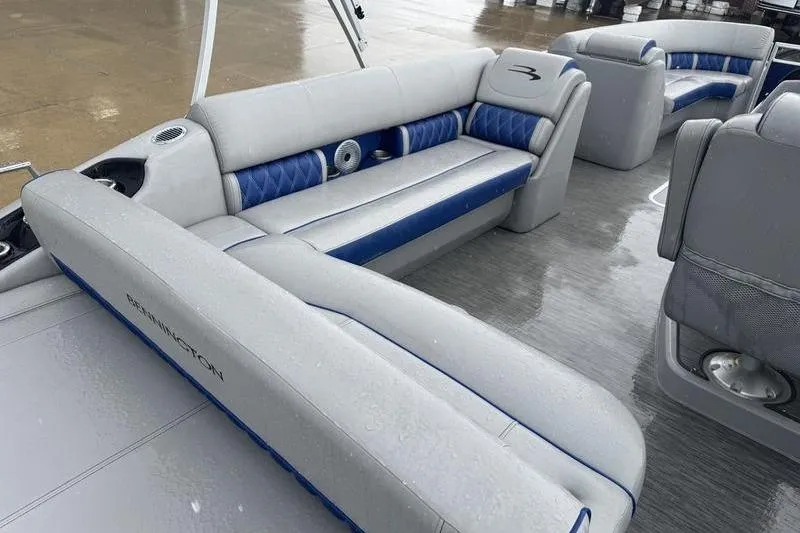 Slide: The Image of 2022 Bennington 26 LXSB boat interior with gray and blue seating on wet deck. - 13