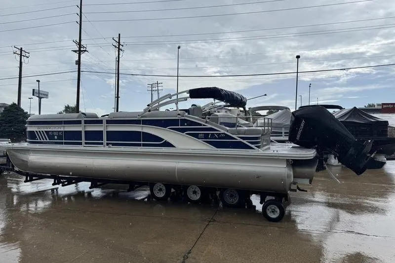 Slide: The Image of 2022 Bennington 26 LXSB pontoon boat on trailer in a parking lot. - 16
