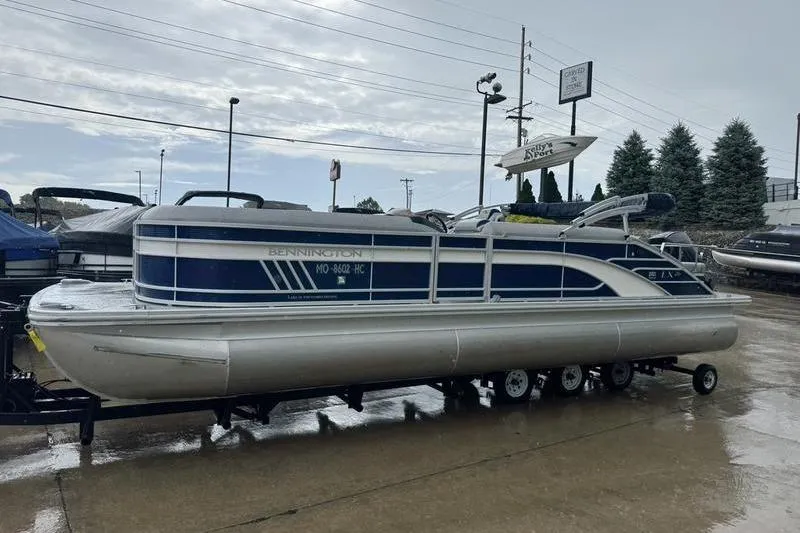 Slide: The Image of 2022 Bennington 26 LXSB pontoon boat on trailer in a marina setting. - 17