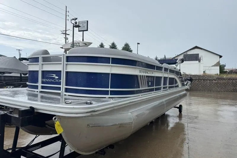 Slide: The Image of 2022 Bennington 26 LXSB pontoon boat on trailer in a parking lot. - 18