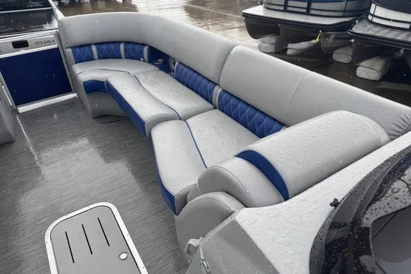 Slide: The Image of 2022 Bennington 26 LXSB boat interior with gray and blue seating, wet from rain. - 4
