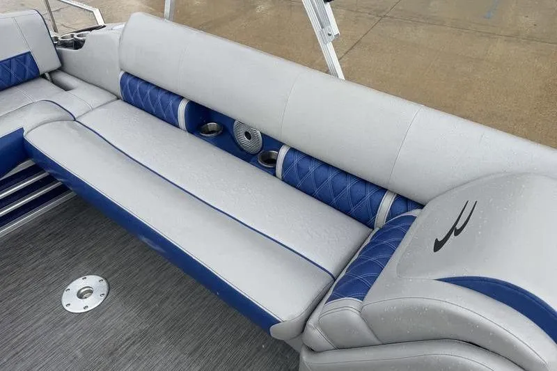 Slide: The Image of 2022 Bennington 26 LXSB boat interior with blue and gray seating, cup holders, and speaker. - 9