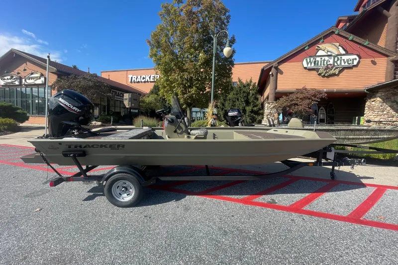 The Image of 2026 Tracker Grizzly 1860 CC boat on trailer outside dealership, "We Take Trades" sign visible. - 0