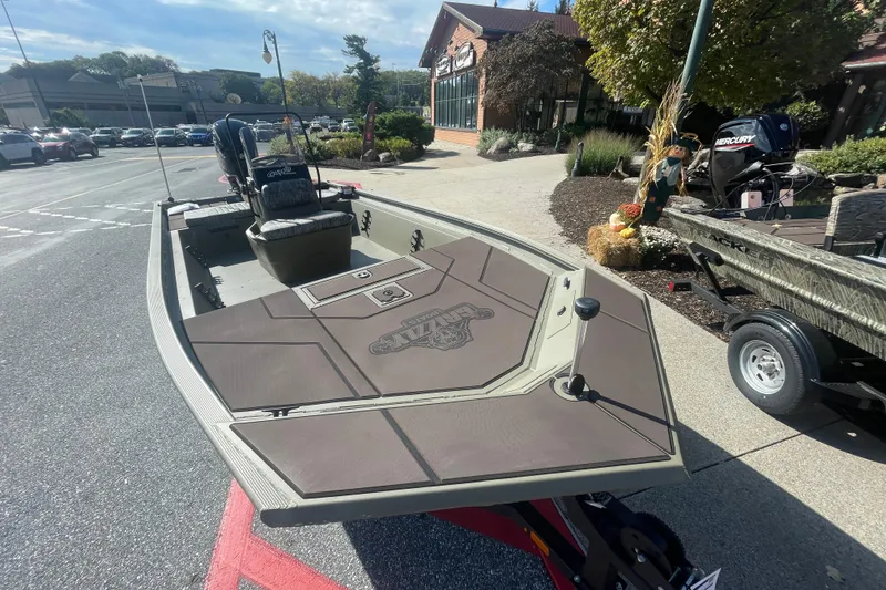 Slide: The Image of 2026 Tracker Grizzly 1860 CC boat with Mercury engine, parked outdoors near a building. - 2