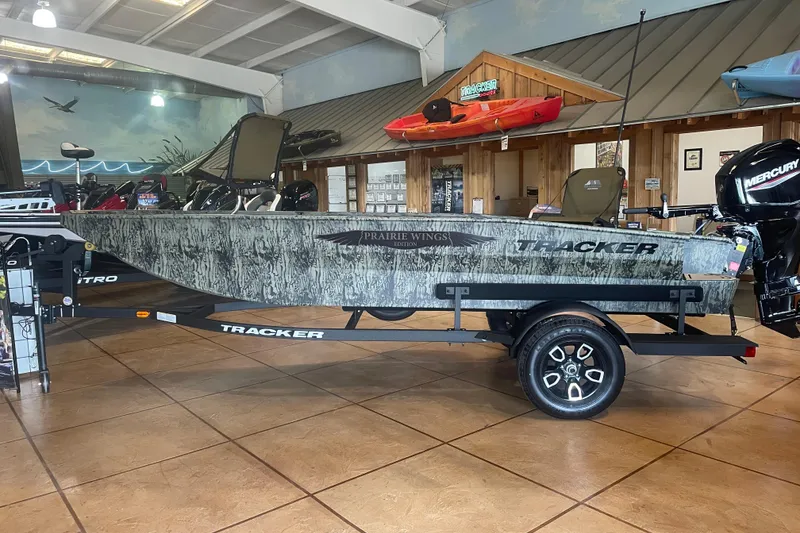 The Image of 2026 Tracker Grizzly 1650 T Prairie Wings Edition boat displayed indoors on a trailer. - 0