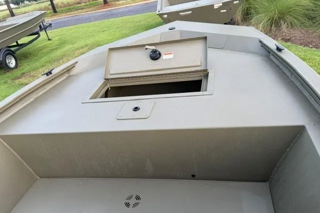 Slide: The Image of 2026 Tracker Grizzly 1648 SC boat with open storage compartment on grassy area. - 6