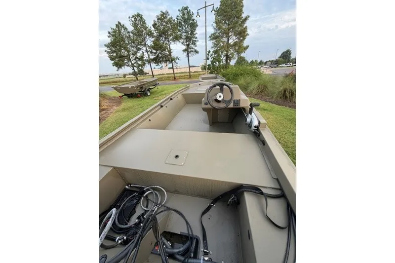 Slide: The Image of 2026 Tracker Grizzly 1648 SC boat interior with steering wheel, parked outdoors. - 7