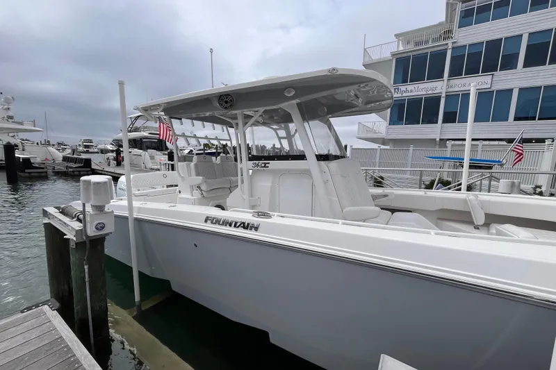 Slide: The Image of 2025 Fountain 34 CC boat docked at marina, overcast sky, American flag displayed. - 7