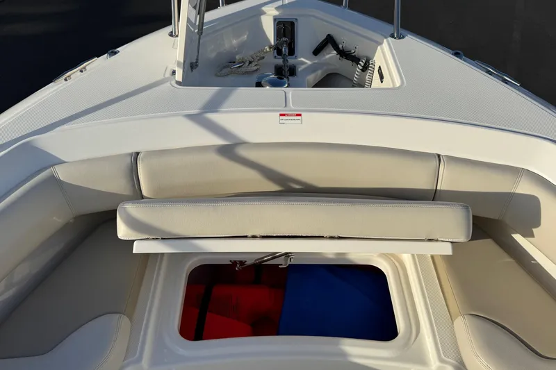 Slide: The Image of 2021 Boston Whaler 280 Outrage boat interior with cushioned seating and storage compartment. - 6