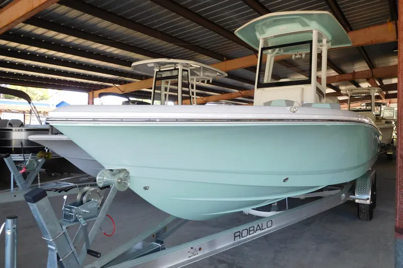 Slide: The Image of 2025 Robalo 246 Cayman boat in storage, light blue hull, on a trailer. - 2
