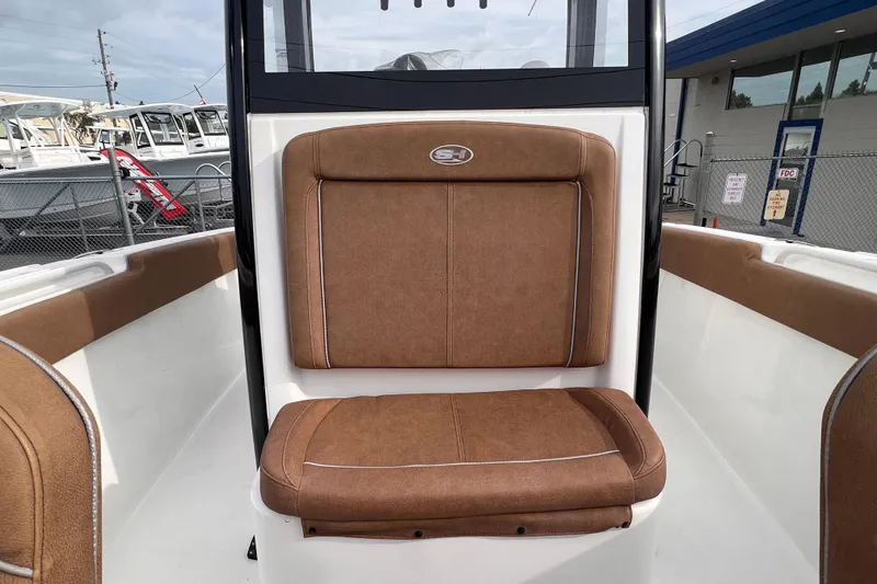 Slide: The Image of 2023 Sea Hunt Ultra 265 SE boat with brown cushioned seating in a marina setting. - 11
