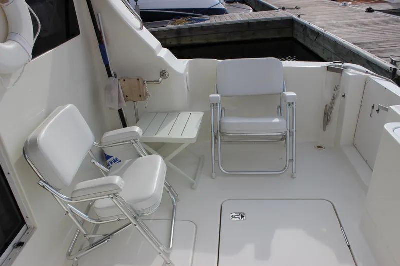 Slide: The Image of 2007 Silverton 36 Convertible yacht deck with white chairs and table. - 16